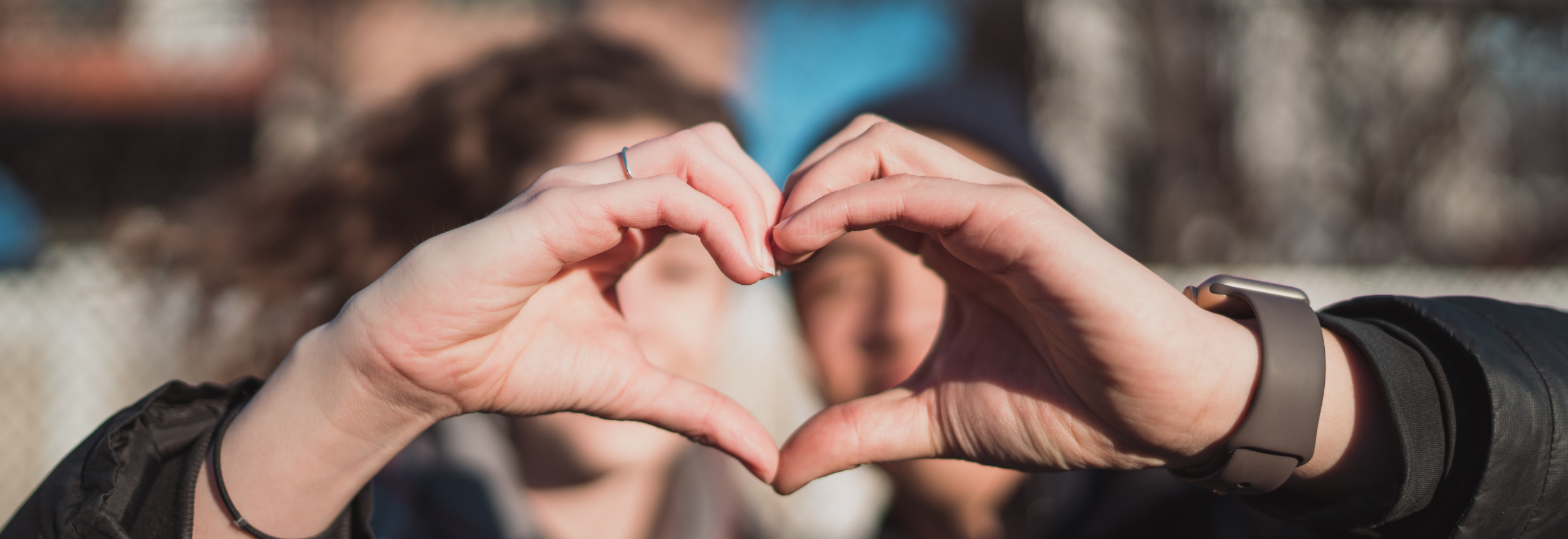 A male and female making a heart shape with one of their hands each.
